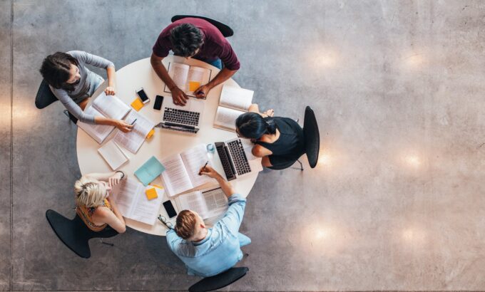 Top view of group of students sitting together at table. University students doing group study.