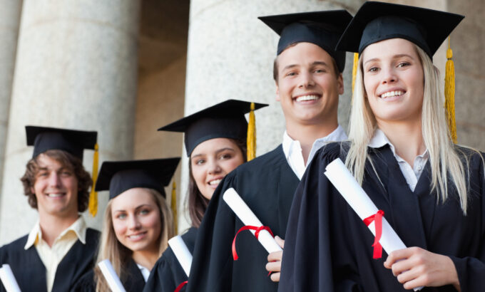 Close-up,Of,Five,Smiling,Graduates,Posing,In,Front,Of,The